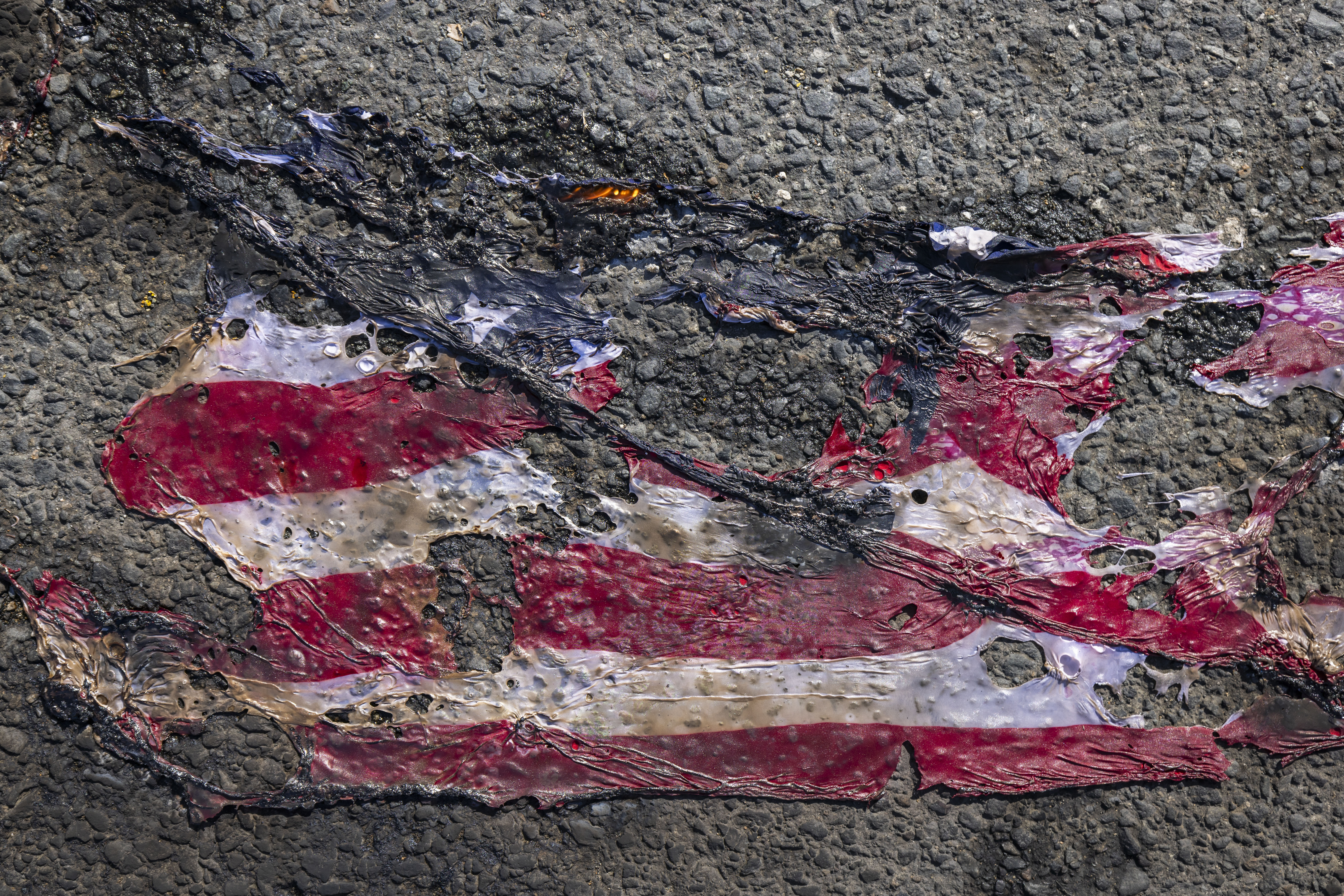 What remains of a U.S. flag covers the street after it was burned during a protest against the visit of U.S. Vice President Kamala Harris in San Juan, Puerto Rico, Friday, March 22, 2024. (AP Photo/Alejandro Granadillo)
